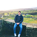 male student sitting in front of scenery