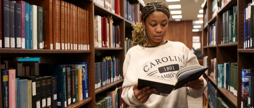 student looking a book in the library