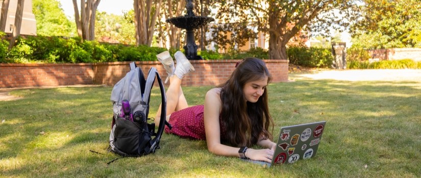 Student working on laptop outside in the grass