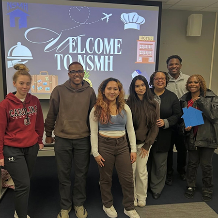 Members of the National Society of Minorities in Hospitality pose in a classroom after a meeting