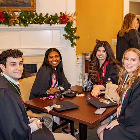 Four December 2022 HRSM graduates pose for a photo inside McCutchen House.
