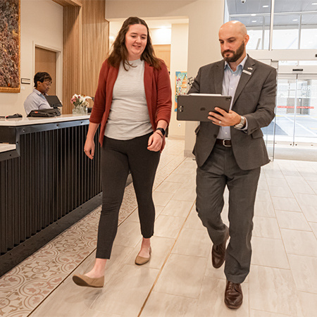 Two hotel managers walking while looking at a tablet