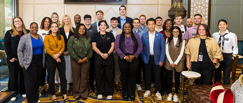 A group of professionally dressed students and staff from the University of South Carolina’s College of Hospitality, Retail and Sport Management pose together inside Atlanta’s historic Fox Theatre during an experiential learning trip.