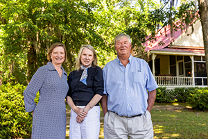 three people standing in front of a house