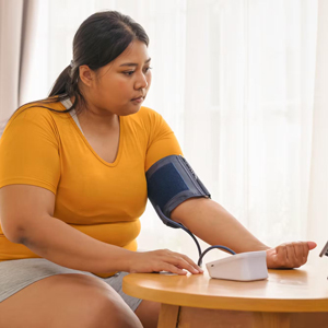 Young woman checks her blood pressure with a monitoring cuff.