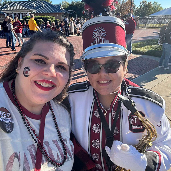 Rhaynie Bongiorno in a Carolina band uniform stands with her sister at a pep rally.