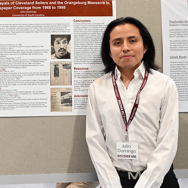 Julio Domingo stands in front of a research poster board display.