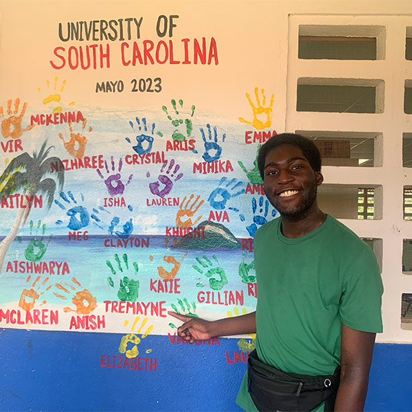 Photo of Tremayne Ansani in front of a wall with handprints
