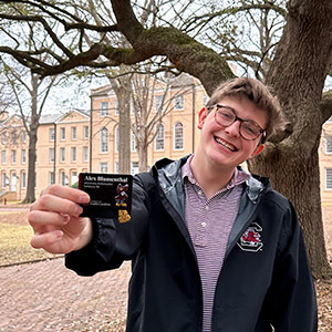 Alex Blumentha holds his University Ambassador ID card