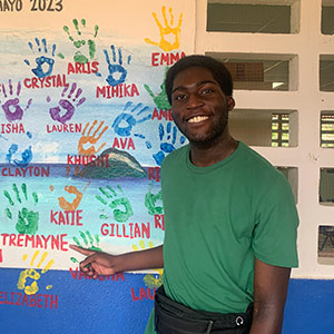 Tremayne Ansani stands near a wall of handprints on a study abroad trip.